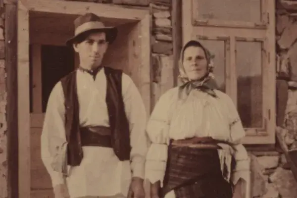 76.) Asszony és férfi viseletben a ház előtt. Gyimes, 1960-as évek