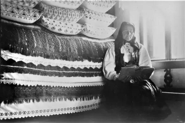 47.) Asszony olvasás közben egy tisztaszobában, vetett ágy előtt. Mezőkeszü, 1960-as évek